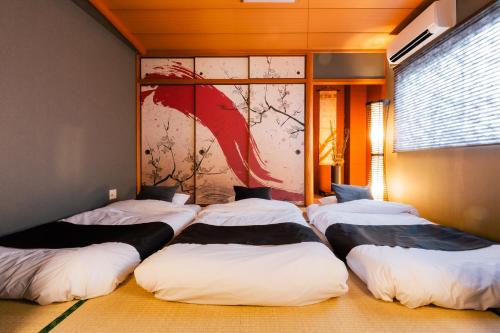 a group of four beds in a room with a painting at Kashikiri Ikkenya YUME in Osaka