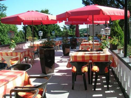 a restaurant with tables and red umbrellas on a sidewalk at Hotel Am Sonnenhang in Kassel
