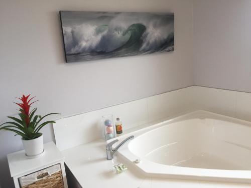 a bath tub in a bathroom with a painting on the wall at Havenlee Homestay in Westport