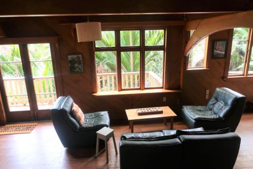 a living room with couches and a table and windows at Te Nikau Retreat in Punakaiki