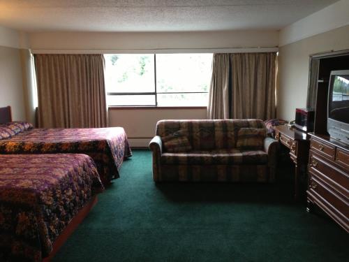 a hotel room with a bed and a couch and a tv at Moby Dick Inn in Prince Rupert