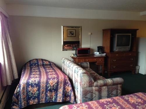a hotel room with a couch and a desk and a television at Moby Dick Inn in Prince Rupert