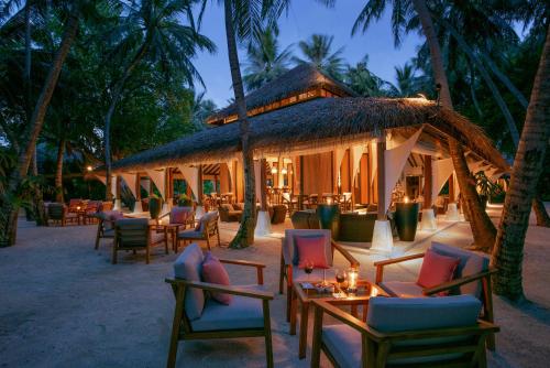 a patio area with tables, chairs and umbrellas at Baros Maldives in Male City