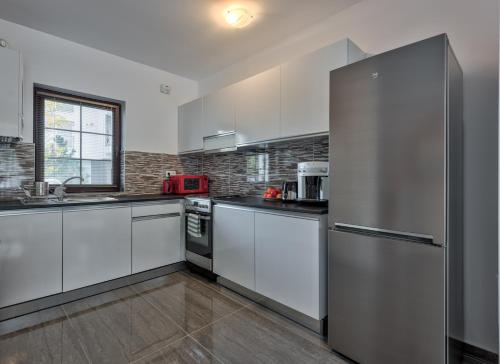 a kitchen with white cabinets and a stainless steel refrigerator at Bucharest Airport Suites & Villas in Otopeni