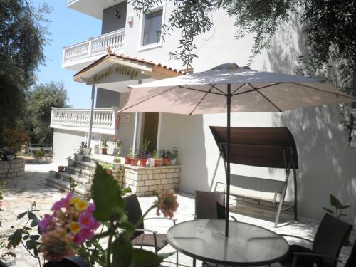 a table with an umbrella in front of a house at Kanali Village Parga in Parga