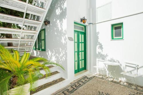 a white house with a green door and a plant at Xenones Lindos in Líndos