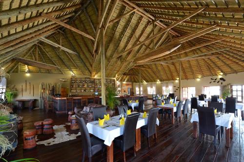 a dining room with tables and chairs in a building at Gondwana Hakusembe River Lodge in Rundu