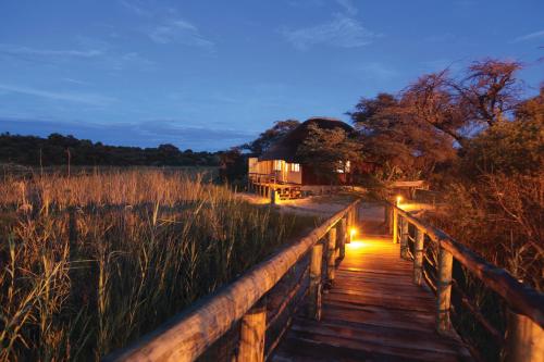 a wooden bridge with lights in a field at Gondwana Hakusembe River Lodge in Rundu