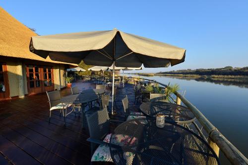 a wooden deck with tables and chairs and umbrellas at Gondwana Hakusembe River Lodge in Rundu