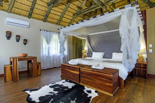 1 dormitorio con cama con dosel y suelo de madera en Gondwana Hakusembe River Lodge, en Rundu