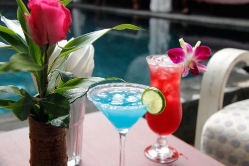 two cocktails on a table with a vase of flowers at Cambana d'Angkor Suites in Siem Reap
