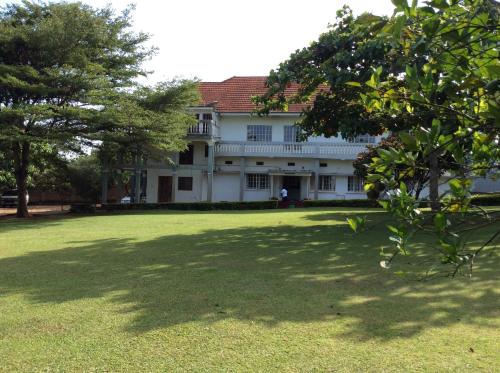 a white house sitting in the middle of a lush green field at Skyway Hotel in Entebbe