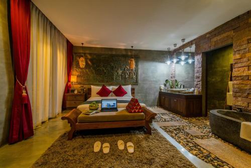 a bedroom with a bed and a bathroom with a tub at Cambana d'Angkor Suites in Siem Reap