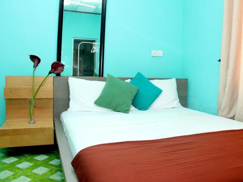 uma cama com duas almofadas e um vaso com uma flor em Marina Resort em Mirissa