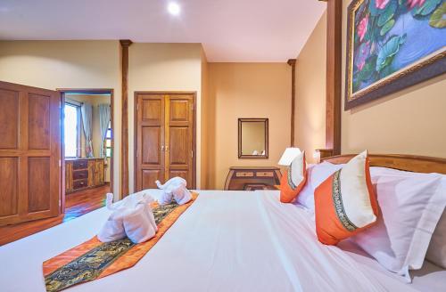 a bedroom with a white bed with towels on it at Mina Garden Villa Resort in Chiang Mai