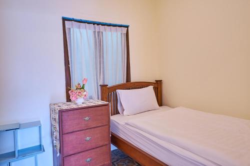 a bedroom with a bed and a dresser and a window at Mina Garden Villa Resort in Chiang Mai