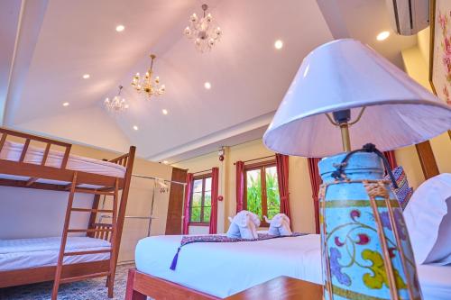 a bedroom with two bunk beds and a lamp at Mina Garden Villa Resort in Chiang Mai