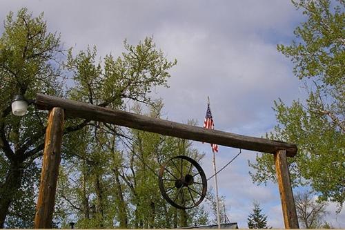 a wooden pole with a wheel and an american flag at Parade Rest Ranch in West Yellowstone
