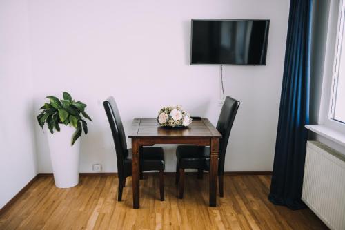a dining room table with four chairs and a television at Hotel Bellevue in Kranj