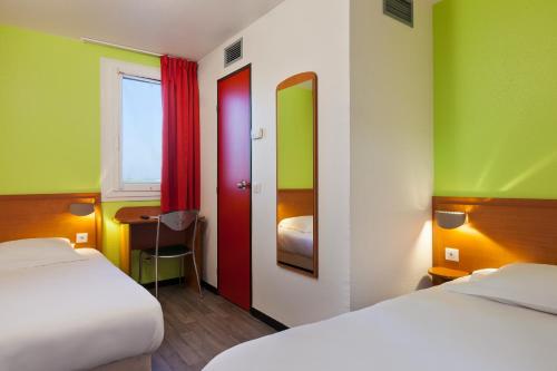 a room with two beds and a desk and a window at ENZO HOTELS Chalons en Champagne in Saint-Martin-sur-le-Pré