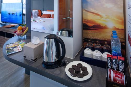 7 Days Premium Hotel Pattaya في جنوب باتايا: كونتر مع آلة صنع القهوة وصحن من الكعك