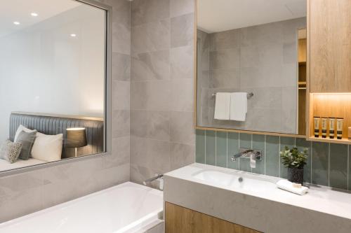 a bathroom with a tub, sink and mirror at Ingot Hotel Perth, Ascend Hotel Collection in Perth
