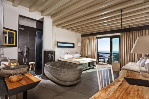 a living room filled with furniture and a large window at Myconian Utopia Relais & Chateaux in Elia Beach