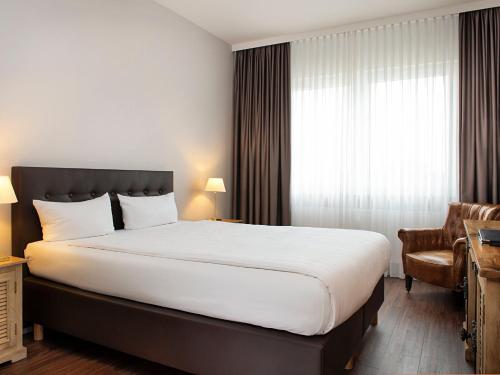 ein Hotelzimmer mit einem großen Bett und einem Fenster in der Unterkunft Victor's Residenz-Hotel Saarlouis in Saarlouis