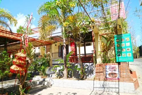 a building with palm trees in front of it at Taste of Bali Hostel in Kuta