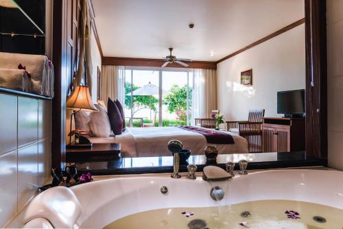 a bathroom with a tub and a bedroom with a bed at Layalina Hotel in Kamala Beach
