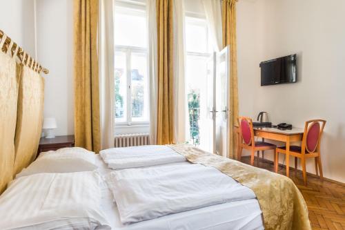 um quarto com uma cama, uma mesa e uma janela em La Fenice em Praga