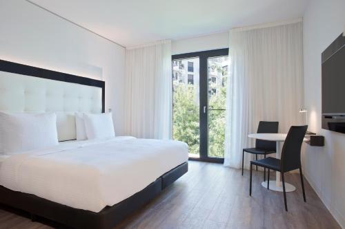 a bedroom with a bed and a table with a chair at INNSiDE by Meliá Frankfurt Ostend in Frankfurt/Main