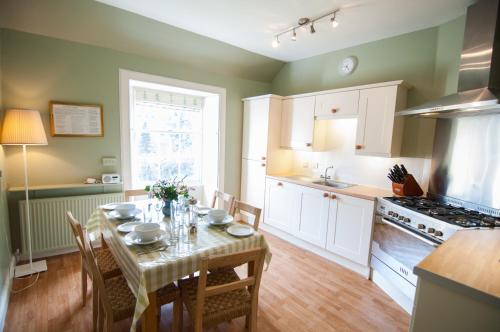 a kitchen with a table with chairs and a kitchen with a stove at Neidpath Castle Cottage in Peebles