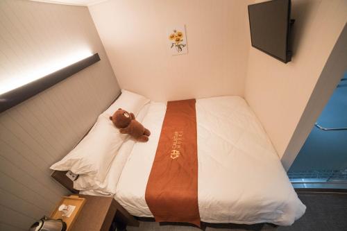 a small room with a bed with a teddy bear on it at Calistar Hotel in Seoul