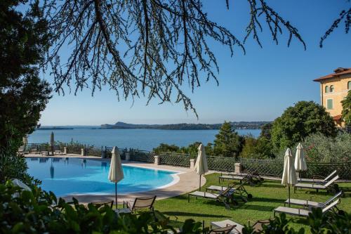 einen Pool mit Sonnenschirmen und Blick auf das Wasser in der Unterkunft Hotel Villa Del Sogno in Gardone Riviera