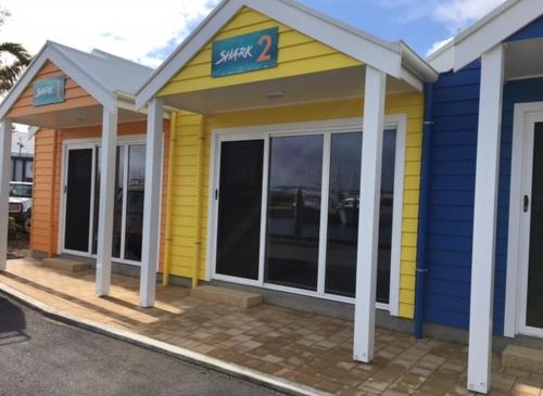 un bâtiment jaune et bleu avec un panneau sur lequel figure un panneau dans l'établissement Port Lincoln Shark Apartment 2, à Port Lincoln