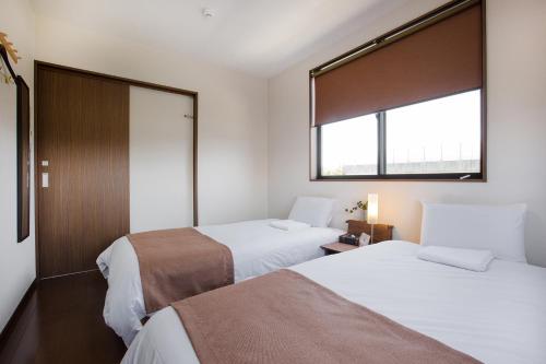 two beds in a small room with a window at Racine Home Harie in Takashima