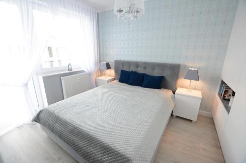 コウォブジェクにあるApartamenty NAVIGATOR-Bliżej Morza 94の白いベッドルーム(青い枕の大型ベッド付)