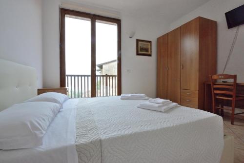 a bedroom with a large white bed and a window at Albergo Navene in Malcesine