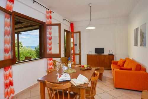a living room with a table and an orange couch at Case di Calamazzo in Scopello