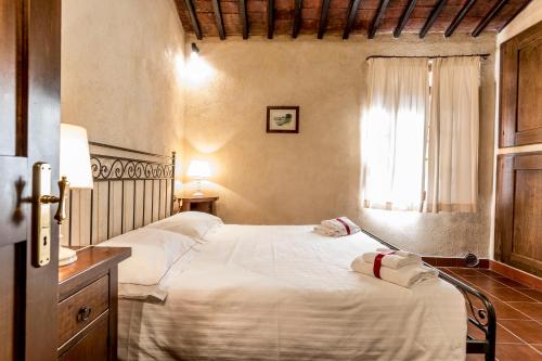 a bedroom with a bed with white sheets and a window at Borgo Il Poggiaccio Residenza d'Epoca in Sovicille