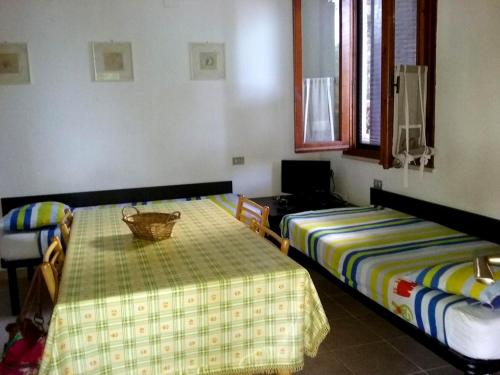 a room with two beds and a table and a window at MERAVIGLIOSO VILLINO DIRETTAMENTE SUL MARE con posto auto e aria condizionata! in Capoliveri