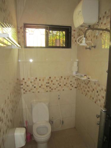 a white bathroom with a toilet and a window at Jakicha Motel in Dar es Salaam