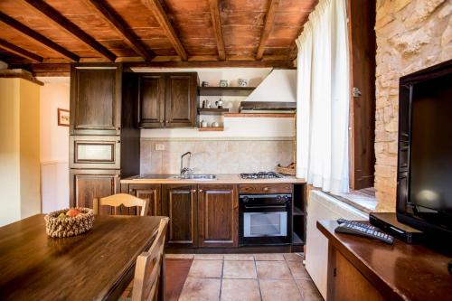 a kitchen with wooden cabinets and a table and a television at Borgo Il Poggiaccio Residenza d'Epoca in Sovicille