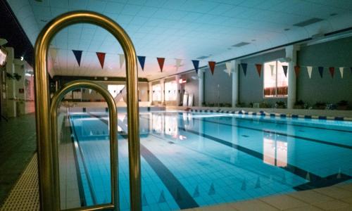 a large swimming pool with blue water in a building at Santasport Apartment Hotel in Rovaniemi