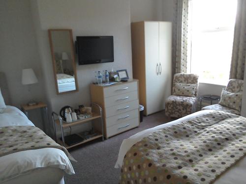 South Lodge Guest House في بريدلينغتون: غرفة نوم مع سرير وخزانة مع تلفزيون