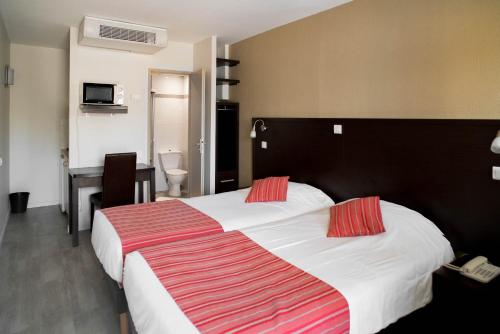 um quarto de hotel com uma cama grande com almofadas vermelhas em Top Motel em Istres