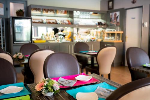 a dining room with tables and chairs with flowers on them at Top Motel in Istres
