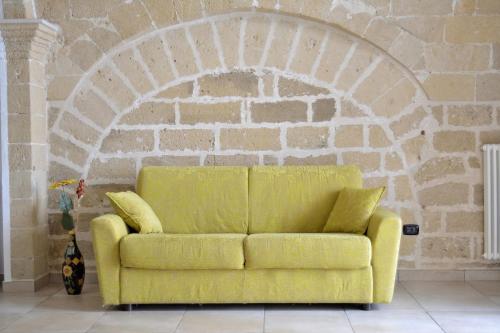 a yellow couch in a room with a brick wall at Borgo Saraceno in Spinazzola