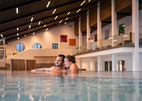 a man and woman laying in a swimming pool at Appartement-Haus Blumenhof in Bad Griesbach
